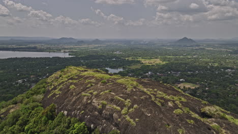 Dambulla-Sri-Lanka-Antena-V5-Sobrevuelo-Inverso-De-La-Montaña-Isigili-Que-Captura-El-Templo-De-La-Cueva-Real,-El-Templo-De-Uyanwatta-En-La-Ladera-Y-El-Paisaje-Circundante-De-La-Ciudad-Del-Pueblo---Filmado-Con-Cine-Mavic-3---Abril-De-2023