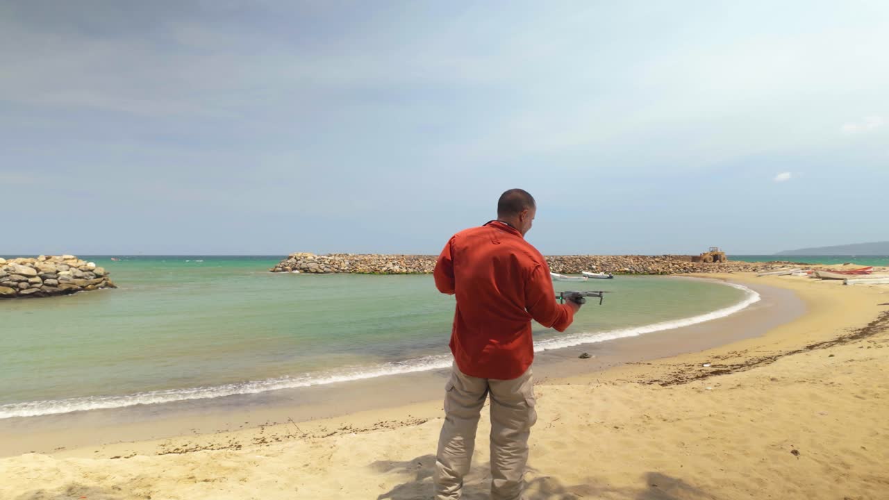 Man Professional photographer controlling drone landing on his hands. Caribbean beach background