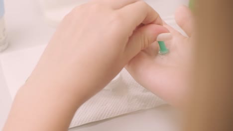 the young girl instill eye drops before installing night time contact lenses in an ophthalmologist's office. bottle with lens solution and case with contact lenses on table.