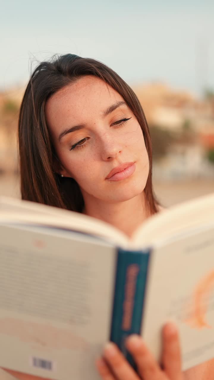 Woman reading a book indoors with eyes closed