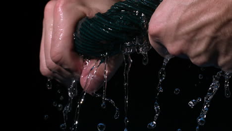 hands wringing out washrag on black background