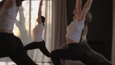 clase de yoga de mujeres maduras sanas que practican pose guerrera disfrutando del ejercicio físico matutino en el estudio al amanecer.