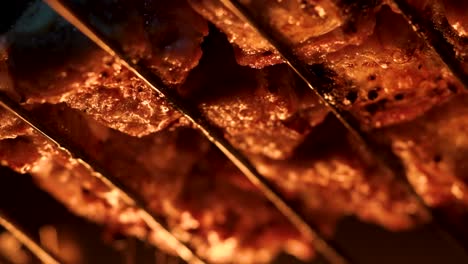 cooking pieces of meat at the grill over intense fire, close up macro shot