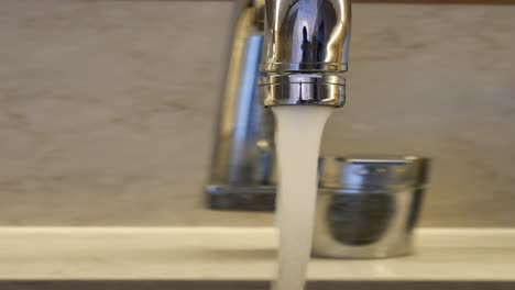 close-up of a chrome faucet with water running