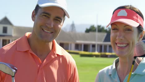 portrait of smiling couple standing with golf club