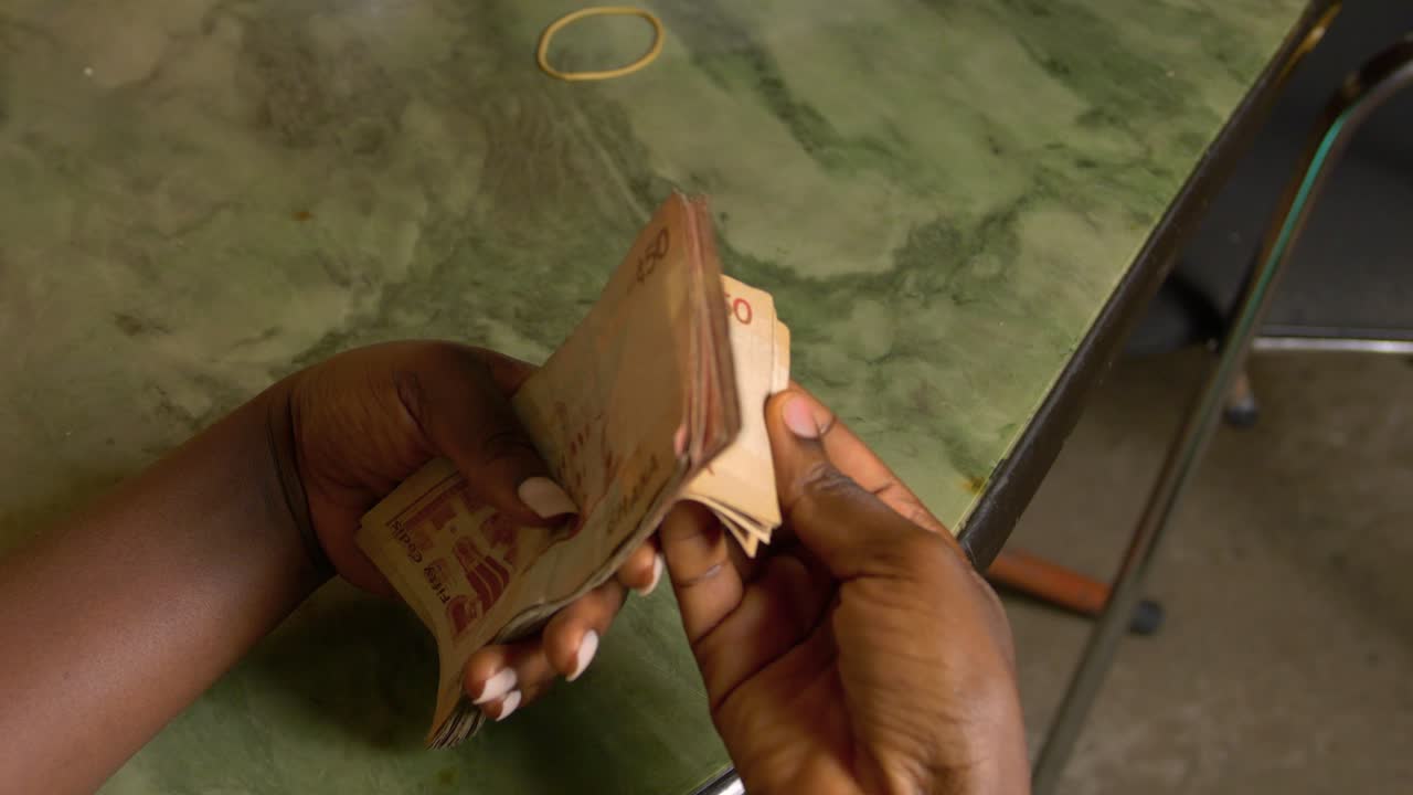 close up of black female african hands counting banknotes Ghanaian cedi currency of Republic of Ghana