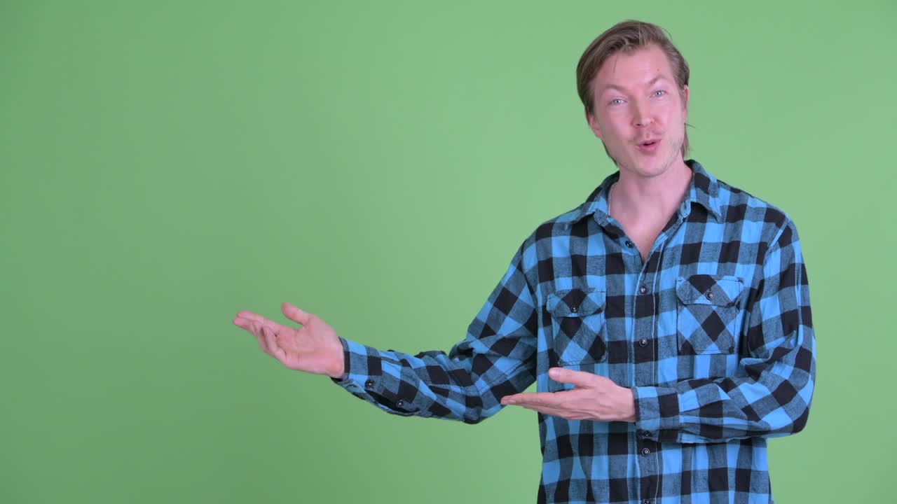 retrato de un hombre caucásico hablando y sonriendo mientras muestra el espacio de copia disparado contra el fondo verde del estudio