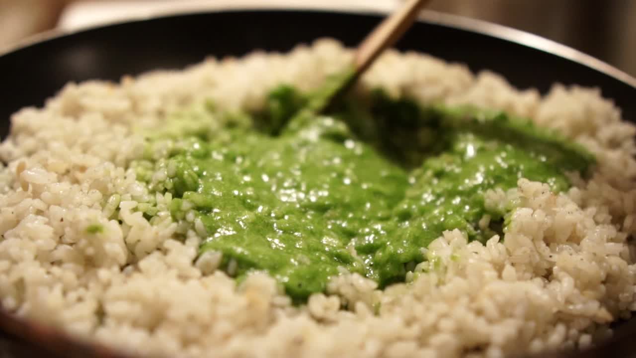 revolviendo el puré de espinacas verdes en el risotto en la sartén, cámara lenta
