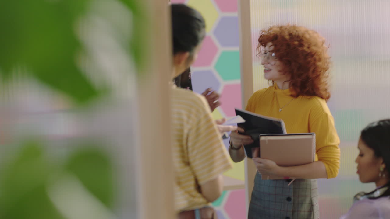 grupo de diversas personas de negocios que se reúnen cabeza de equipo pelirroja mujer que comparte documentos de proyectos estudiantes creativos que trabajan juntos haciendo lluvia de ideas en un colorido lugar de trabajo de oficina