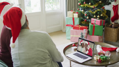 Diverse-senior-female-friends-using-laptop-for-christmas-video-call-with-happy-couple-on-screen