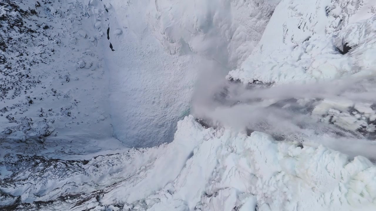 Vista aérea de cima para baixo de um cânion de cachoeira congelada no inverno da Islândia.
