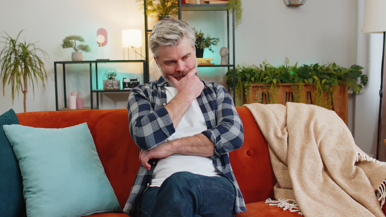 Disappointed man sits at home reflecting on moral distress after quarrel breakup or divorce problem