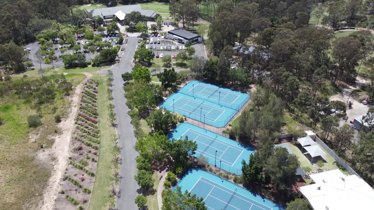 Drone ascending over tennis courts with a golf course and a golf club building in the background in Australia