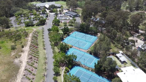drone ascending over tennis courts with a golf course and a golf club building in the background in australia