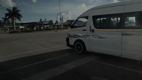 a static shot of a white car which is being used as public transport running on a street