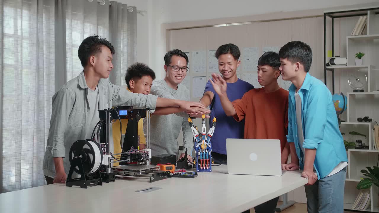 과 3d 프린팅을 가진 아시아 남자와 소년들은 학교에서 사이보그 손에 대해 작업하는 동안 손을 합치고 있습니다.