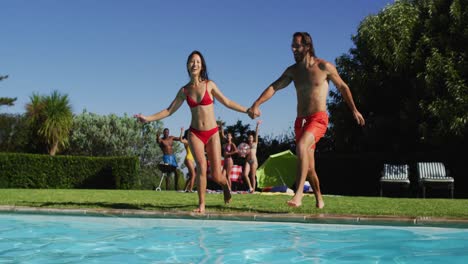 Grupo-Diverso-De-Amigos-Divirtiéndose-Saltando-A-Una-Piscina