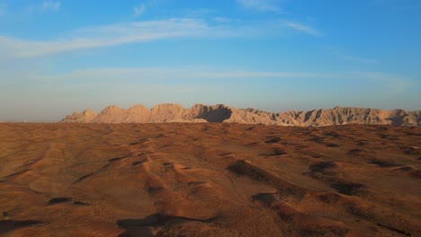 aerial drone view of the arabian desert, the land is transforming from desert to green, mleiha mountains in the background, sharjah, united arab emirates