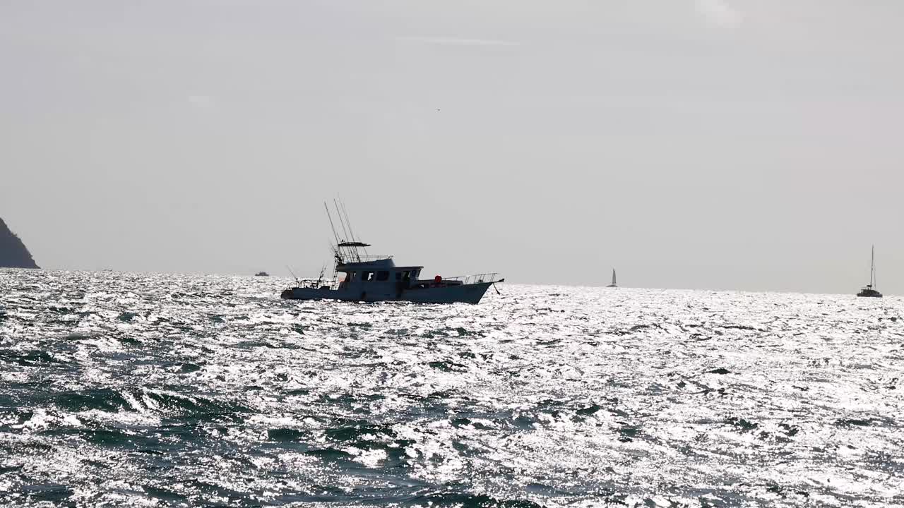 태국 푸켓 근처의 반이는 바다 바다를 가로질러 항해하는 요트, 밝은 낮빛 아래, 평온한 해양 아름다움을 포착합니다.