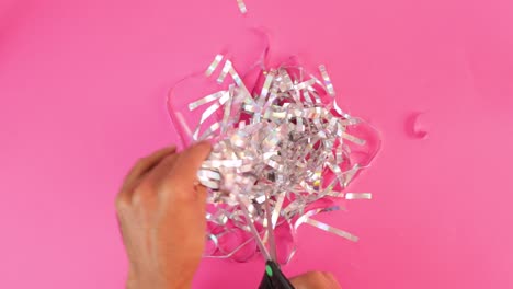cutting iridescent paper strips into silver confetti with scissors