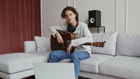 young man playing acoustic guitar on a couch