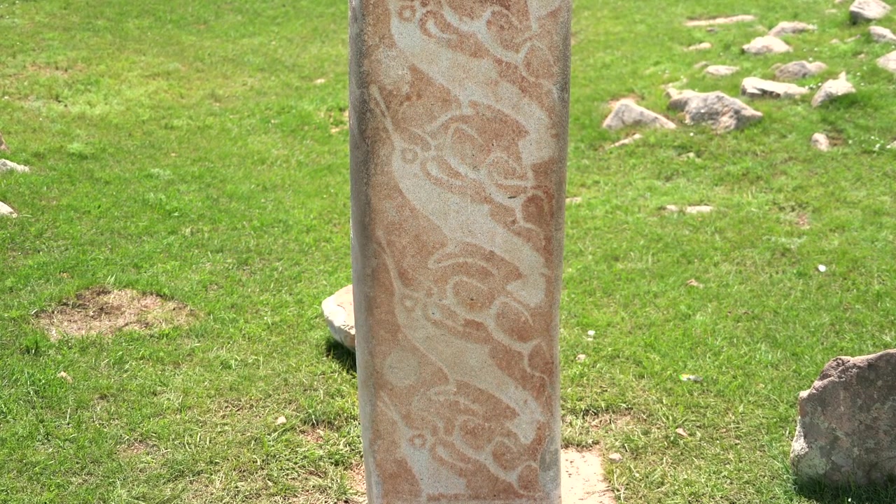 Antica stele di pietra con intagli intricati in un campo erboso