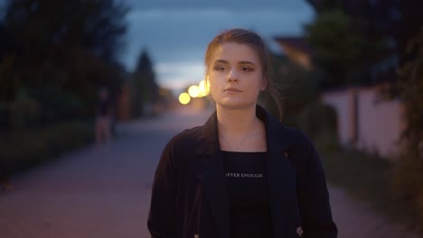 Girl-walking-along-a-lighted-street-at-night