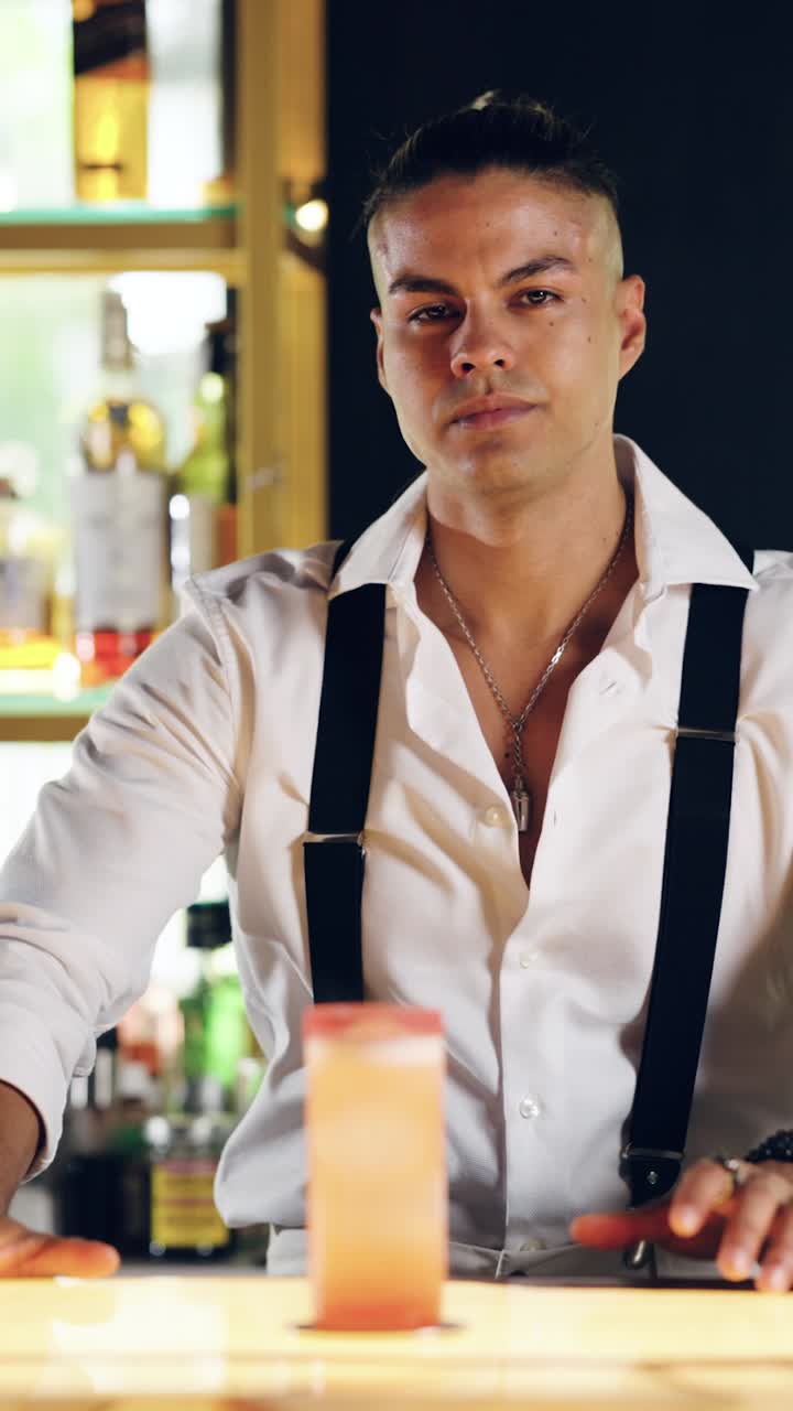 Professional Bartender Places Cocktail on Bar and Looks at Camera
