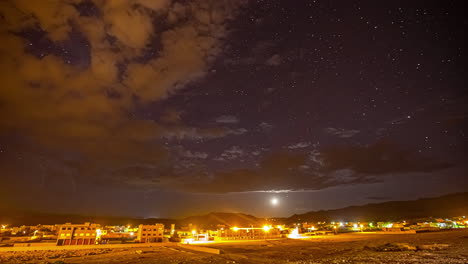 lapso de tiempo del sol desapareciendo en el cielo estrellado y nublado sobre la ciudad de marruecos iluminada por la noche