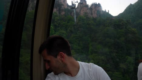 man smiling in cable car admiring tianzi mountain landscape in zhangjiajie, china