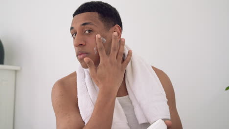 retrato de un hombre negro aplicando crema hidratante. tratamientos y cuidados caseros.