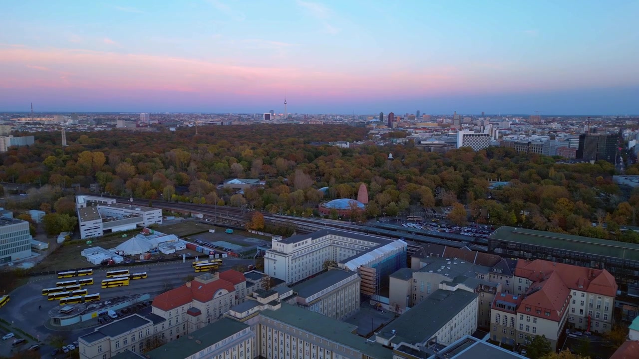 Estação de trem Zoologischer Garten e paisagem urbana circundante em Berlim, Alemanha, durante o pôr do sol. Voo majestoso de drone com vista aérea descendente.