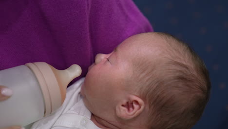 cute little baby is hungry and opening its mouth ready to eat. caring mother gives baby a bottle. baby takes the milk bottle.