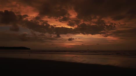 static time-lapse shot of a beautiful sunset at the lake which is reflected by the water with moving clouds and running people