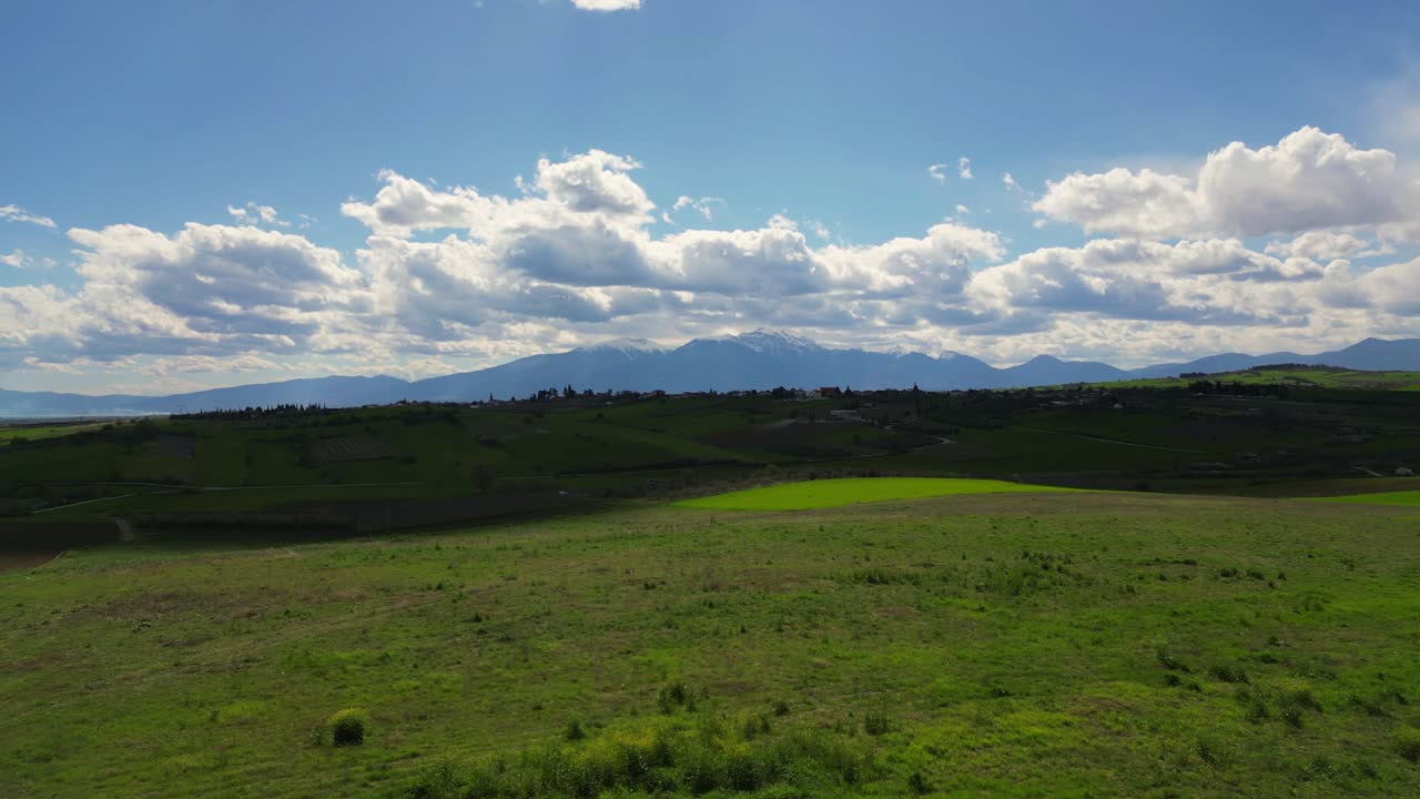 Drone establishing of Olympus mountain range under clear skies, open field and mythology landscape