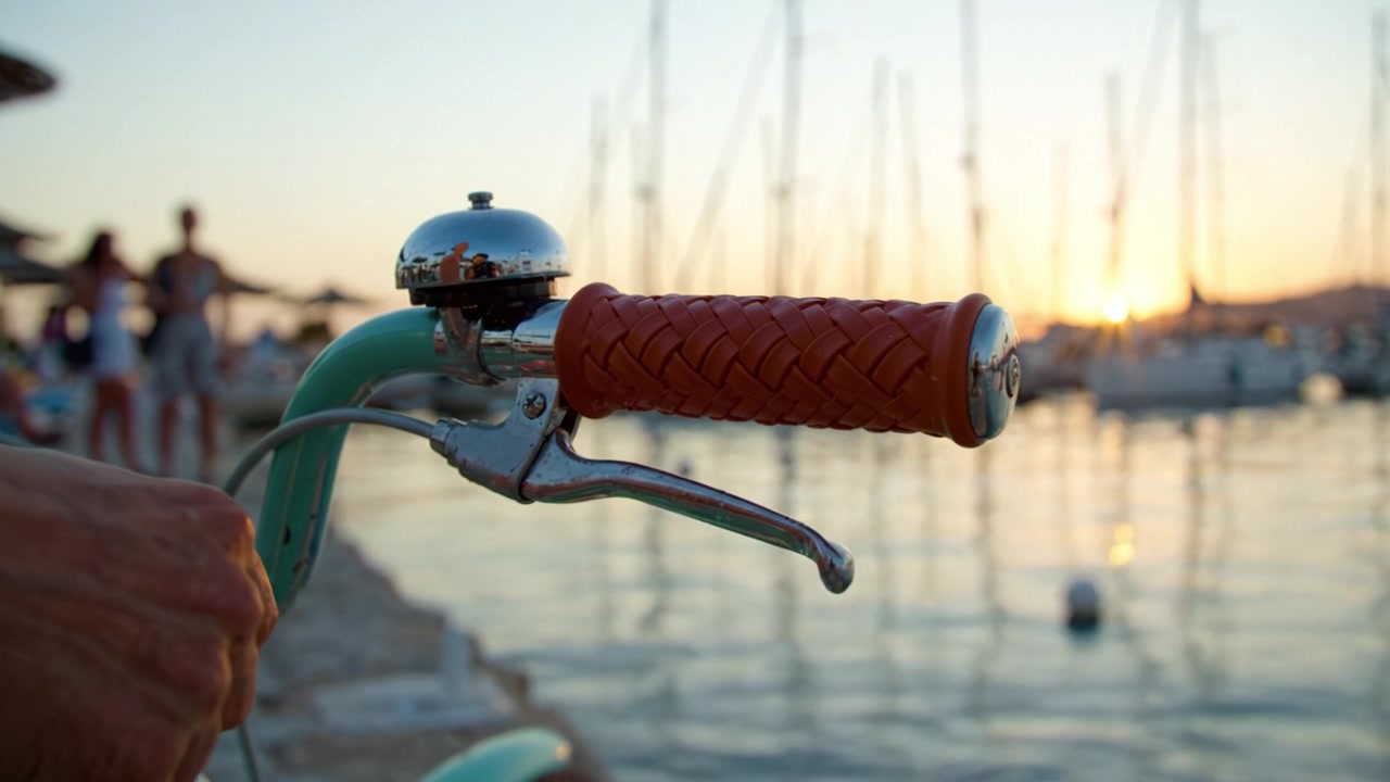 Un bellissimo tramonto al porto con una bicicletta vintage, che mette in mostra il manubrio colorato e le acque riflettenti con barche in silhouette sullo sfondo.