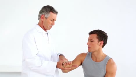 Reifer-Arzt-überprüft-Das-Verletzte-Handgelenk-Des-Sportlers