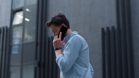 Attractive-businessman-making-phone-call-at-modern-building-talking-to-partner