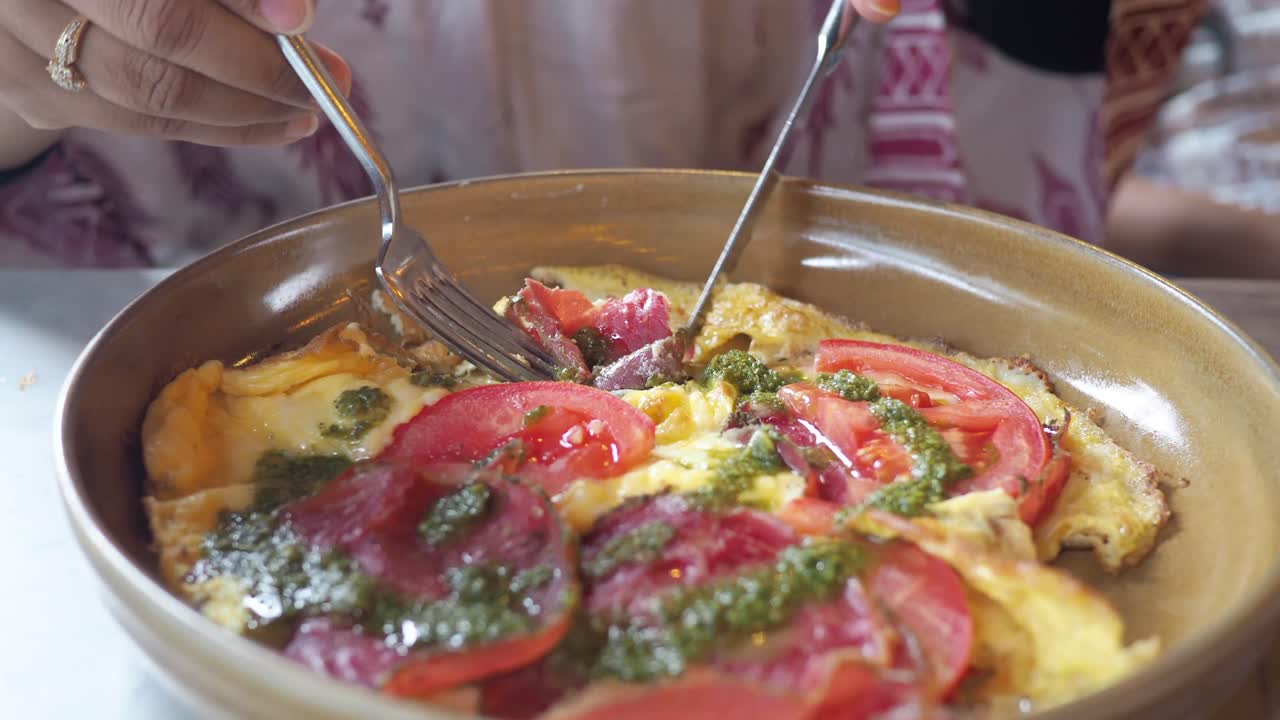 Tortilla con tomate y pesto siendo comida.