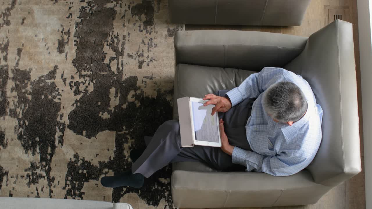 cabeza de un anciano asiático mayor usando una tableta digital en un cómodo hogar 4k