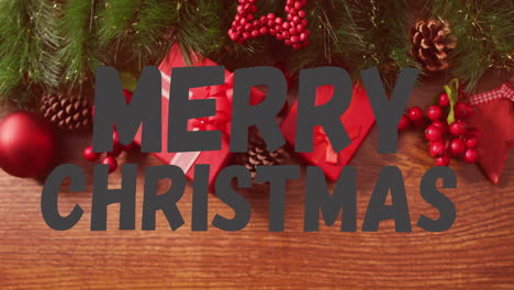 merry christmas text animation over christmas decorations with gifts and pine cones