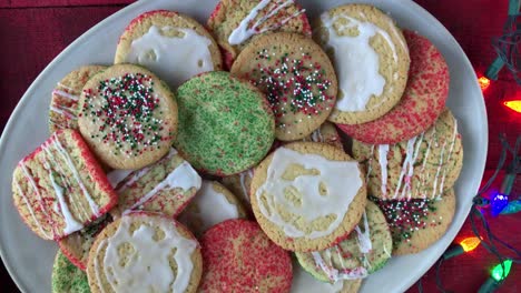 child's-hand-grabbing-Christmas-sugar-cookie-from-pile-of-festive-cookies-top-view