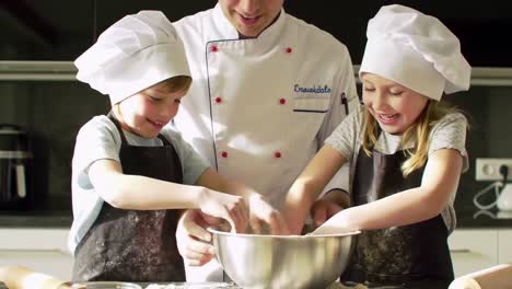 delighted kids and chef preparing delicious dough together in kitchen