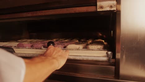 bakery chef making different various of fresh artesian buns and baguettes using traditional recipe close-up. young man kneading dough. artisan bread is making by skill bakers using natural and high-quality ingredients. food with health and flavour benefits. bakery shop and market