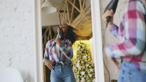 teenage girl singing with hair dryer as microphone at christmas