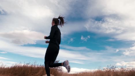 fit young woman in trendy atheltic active wear jogs against a beautiful blue sky