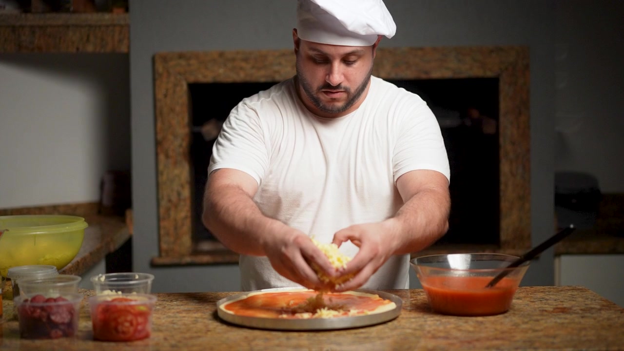 Uno chef professionista sparge con cura formaggio mozzarella appena grattugiato su una base di impasto per pizza condita con una ricca salsa di pomodoro.