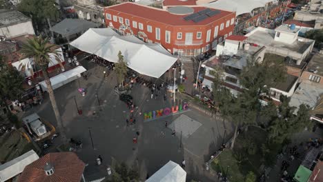 Aerial-orbits-small-Juarez-Plaza-with-city-sign-in-Mixquic,-Mexico