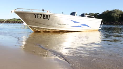 a small boat gradually approaches the sandy shore