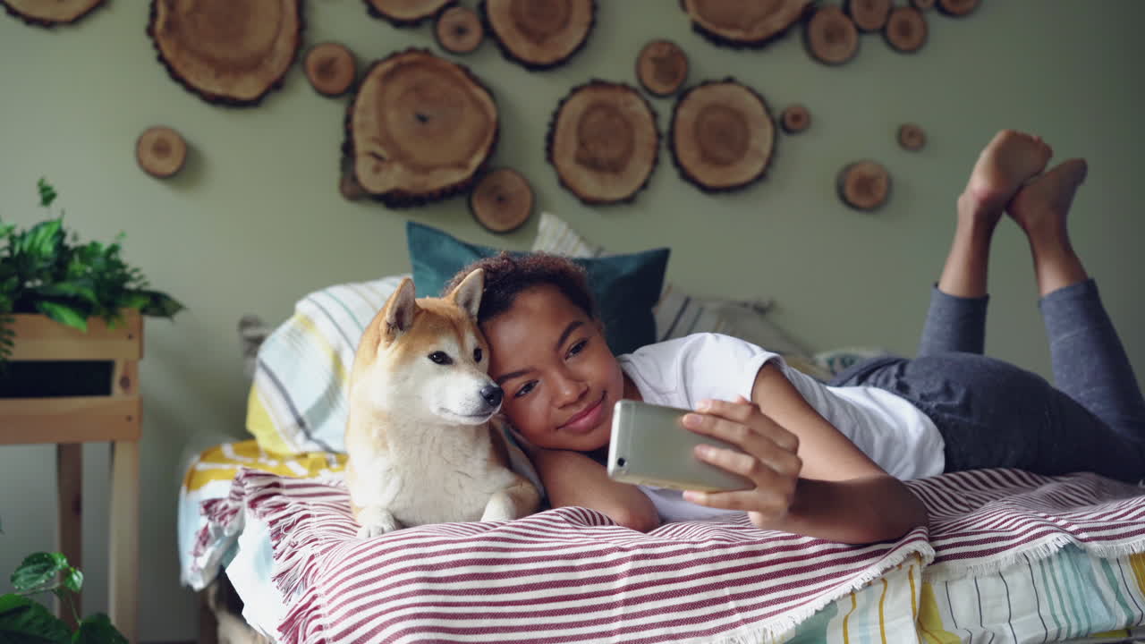 Girl taking selfie with her dog in bedroom